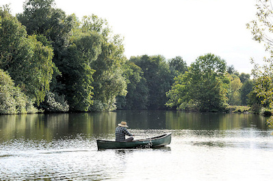 8738 Ein Ruderer mit Strohhut in seinem Ruderboot auf der Dove Elbe - im Hintergrund das Ufer von Hamburg Neuengamme.
